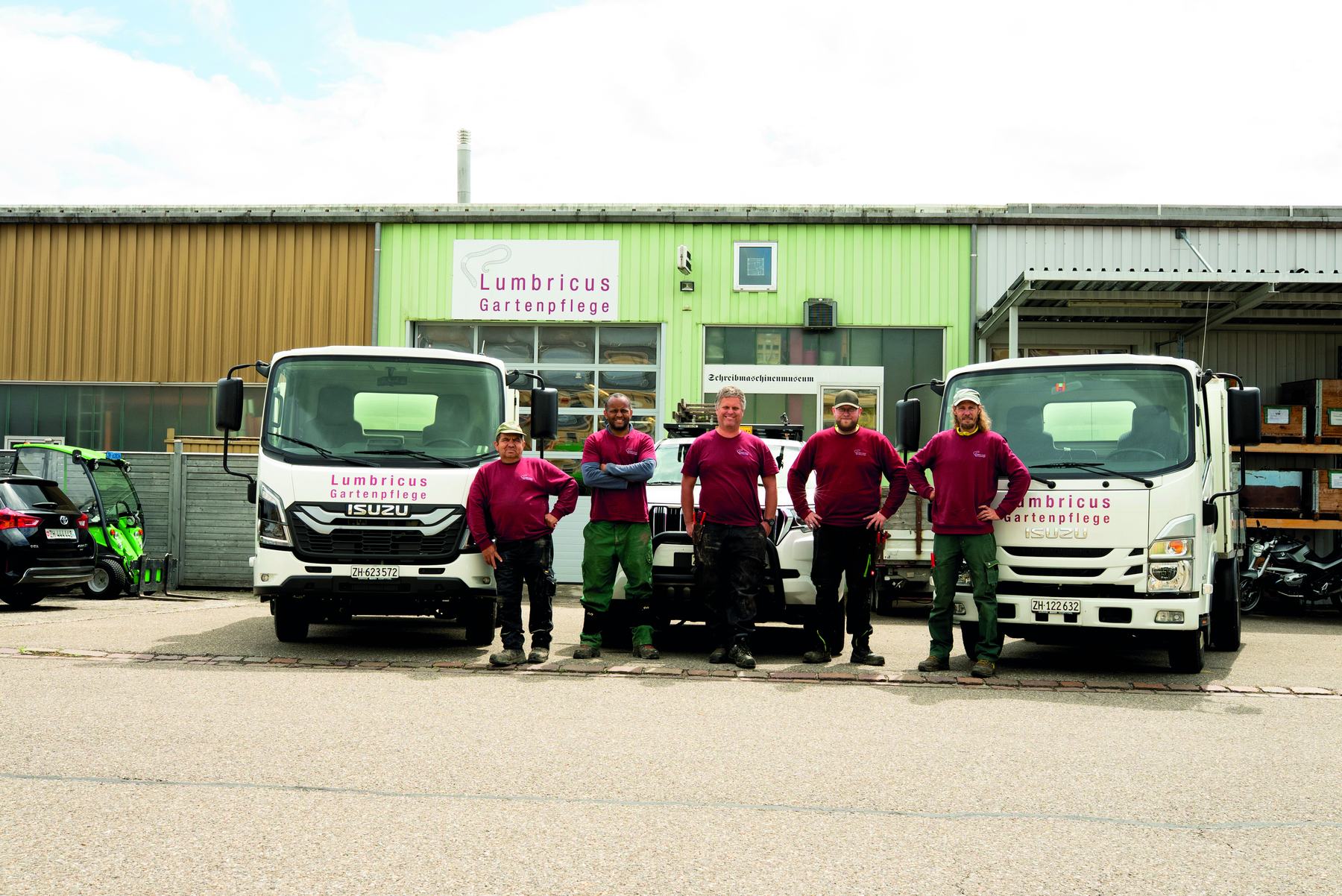 Das Team in roten Lumbricus-Shirts vor drei Lastwagen auf dem Betriebsgelände